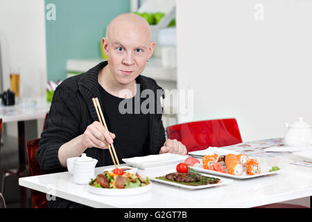 Junger Mann sitzt an der Sushi-bar, Lächeln Stockfoto