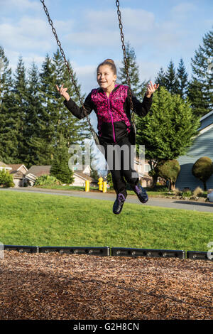 Zehn Jahre altes Mädchen schwingen ohne hängen auf einem Spielplatz in Issaquah, Washington, USA Stockfoto