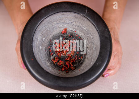Roter Pfeffer in einem Mörser, der Hand wurde gemahlen, zum Eintauchen des Naan-Brot-Teiges vor dem Backen verwenden Stockfoto