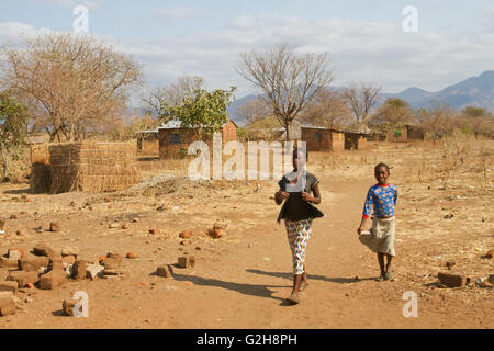 Mädchen zu Fuß durch kleine Ziegel Häuser in der Chiawa Cultural Village auf dem Sambesi-Fluss in Sambia, Afrika Stockfoto