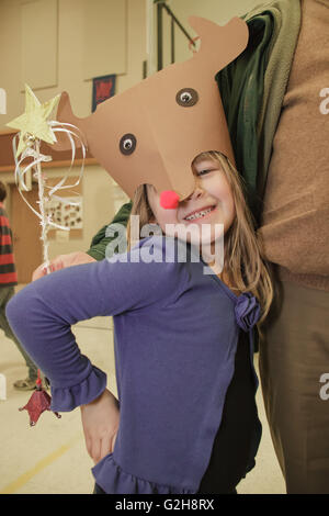 Sechs Jahre altes Mädchen zeigen ihre handgefertigten Rudolf Hut an einer Schule Handwerk Messe, immer eine Umarmung von ihr Großvater Stockfoto