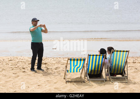 Bournemouth, Dorset, UK 30. Mai 2016. Menschen nehmen Foto des Paares sitzen in Liegestühlen am Strand von Bournemouth auf Bank Holiday Montag an einem bewölkten Tag. Bildnachweis: Carolyn Jenkins/Alamy Live-Nachrichten Stockfoto