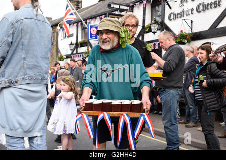 Castleton, Derbyshire, UK. 30. Mai 2016. Alten Garland Zeremonie obwohl die Straßen von Castleton im Peak District. Die Girlande "selbst ist ein Bienenstock förmigen Kopf-Kleid, mit wilden Blumen und grün, die vom König über seinen Kopf und Schultern getragen wird. Die oberste, abnehmbare Stück die Girlande ist bekannt als "The Queen" und ist auch ein kleiner Bienenkorb-Form. Der Kranz oft wiegt zwischen 50 und 60 Pfund und ist sehr schwer, auf des Königs Schultern zu tragen.  Vorbeifahrenden Getränke runden auf Band-Mitglieder. Bildnachweis: Ian Francis/Alamy Live-Nachrichten Stockfoto