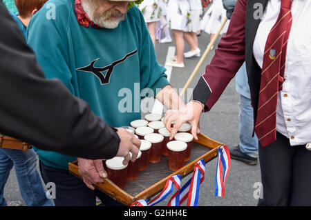 Castleton, Derbyshire, UK. 30. Mai 2016. Alten Garland Zeremonie obwohl die Straßen von Castleton im Peak District. Die Girlande "selbst ist ein Bienenstock förmigen Kopf-Kleid, mit Wildblumen und grün, die vom König über seinen Kopf und Schultern getragen wird. Die oberste, abnehmbare Stück die Girlande ist bekannt als "The Queen" und ist auch ein kleiner Bienenkorb-Form. Der Kranz oft wiegt zwischen 50 und 60 Pfund und ist sehr schwer, auf des Königs Schultern zu tragen.  Getränke an Bandmitglieder übergeben. Bildnachweis: Ian Francis/Alamy Live-Nachrichten Stockfoto