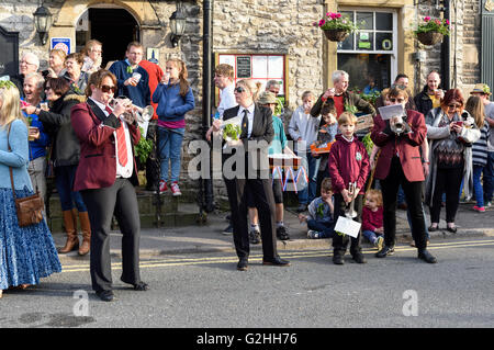 Castleton, Derbyshire, UK. 30. Mai 2016. Alten Garland Zeremonie obwohl die Straßen von Castleton im Peak District. Die Girlande "selbst ist ein Bienenstock förmigen Kopf-Kleid, mit Wildblumen und grün, die vom König über seinen Kopf und Schultern getragen wird. Die oberste, abnehmbare Stück die Girlande ist bekannt als "The Queen" und ist auch ein kleiner Bienenkorb-Form. Der Kranz oft wiegt zwischen 50 und 60 Pfund und ist sehr schwer, auf des Königs Schultern zu tragen. Der König und seine Gemahlin sind Stuart Kostüm gekleidet. Band-Mitglieder-Praxis vor Pub. Bildnachweis: Ian Francis/Alamy Live Stockfoto