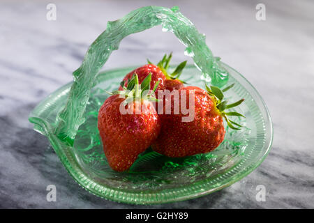 Drei frische Erdbeeren in Vintage grüne Glasschale auf Marmor Stockfoto