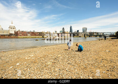 Zwei Kinder spielen am sandigen Ufer der Themse in London bei Ebbe im Sonnenschein Mai 2016 Stockfoto