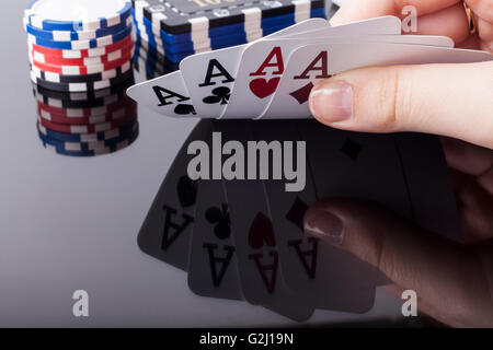 Frau hält Asse Pokerkarten mit Reflexion und Casino-chips im Hintergrund Stockfoto