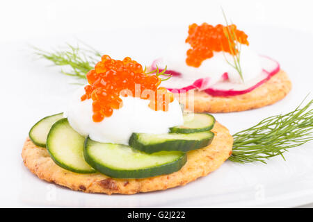 Roter Kaviar auf weißem Käse und grüne Gurke Vorspeise auf weißem Hintergrund Stockfoto