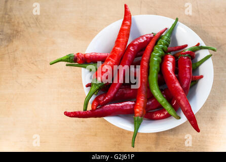 Rote Chili mit einem grünen Cilli Pfeffer in einer Schüssel auf Holz Hintergrund Stockfoto