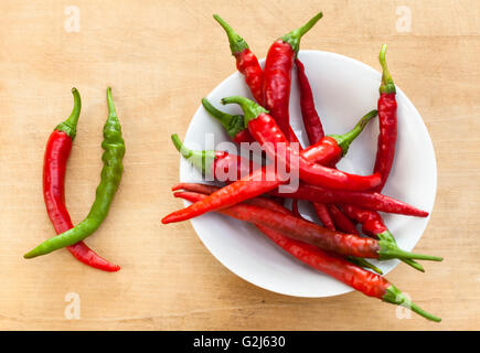 Rote Chili mit einem grünen Cilli Pfeffer in einer Schüssel auf Holz Hintergrund Stockfoto