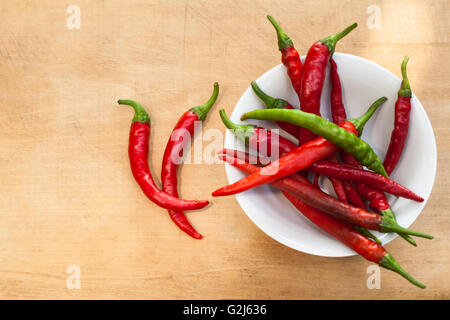 Rote Chili mit einem grünen Cilli Pfeffer in einer Schüssel zwei auf Holz Hintergrund Stockfoto