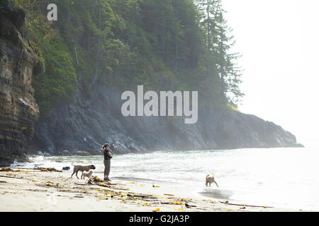 Eine Frau mit drei Hunden in Mystic Beach entlang der Juan de Fuca Trail. Vancouver Island, BC, Kanada. Stockfoto