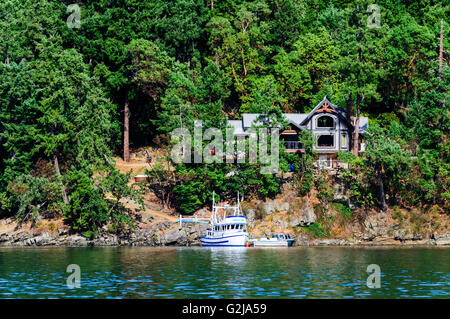 Ein Boot vor Anker vor einer Uferpromenade nach Hause in Maple Bay in der Nähe von Duncan, Britisch-Kolumbien. Stockfoto