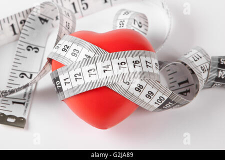 rotes Herz mit Messgerät Curling nahe es auf weißem Hintergrund Stockfoto