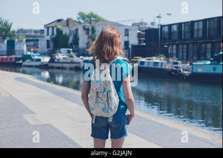 Eine junge Frau steht durch einen Kanal in der Stadt an einem Sommertag Stockfoto