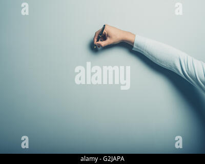 Eine männliche Hand ist auf einer blauen Wand mit einem Stift schreiben. Stockfoto