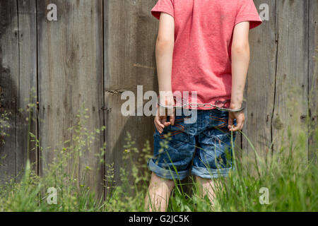 Niedliche kleine Junge mit Handschellen an den Händen, spielen Stockfoto