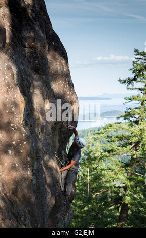 Ein männliche Kletterer führt eine Kletterroute auf einem Platten beim Klettern auf Quadra Island Quadra Island Northern Gulf Islands Stockfoto