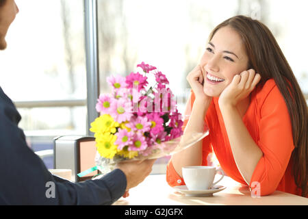 Ehrliche Frau dating in einem Café und auf der Suche nach ihrem Freund, der gibt ihr einen Blumenstrauß Stockfoto