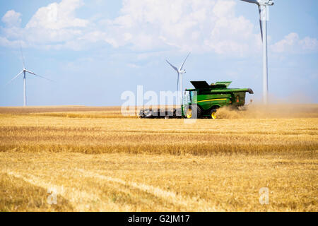 John Deere Mähdrescher erntet Weizen in Oklahoma, USA. Windpark im Hintergrund. Stockfoto