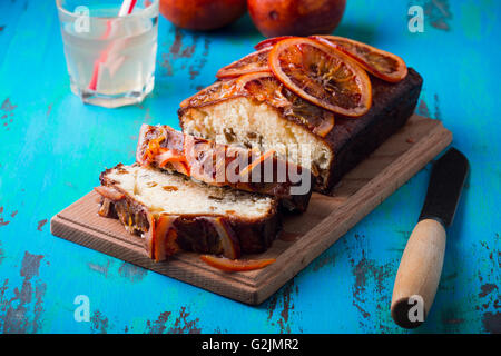 Hausgemachte orange Sandkuchen mit Blutorange Topping auf rustikalen Holztisch Stockfoto