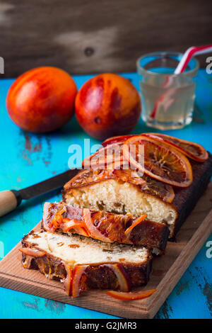 Hausgemachte orange Sandkuchen mit Blutorange Topping auf rustikalen Holztisch Stockfoto