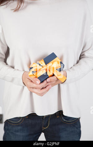 blauen Geschenkbox mit gelben Band Frau Bluejeans Creme Jersey übergibt weißen Hintergrund Stockfoto