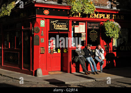 Drei Männer entspannen und telefonieren außerhalb der Tempel Bar Pub in Dublin an einem sonnigen Tag, Irland Stockfoto