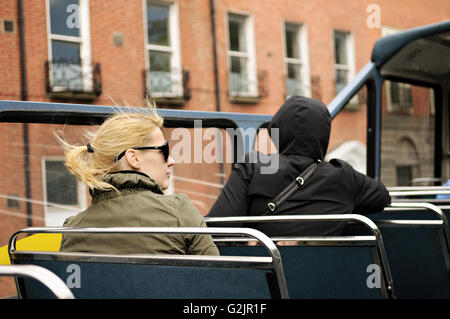 Junge, blonde Frau sitzt auf einem offenen Bus in Dublin, Irland Stockfoto