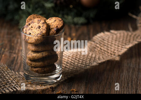 Frisch gebackene Schokoladenkekse in einem Glas auf einem rustikalen Holztisch. Stockfoto