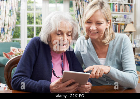 Weibliche Nachbarn zeigt Senior Frau wie Digital-Tablette verwenden Stockfoto