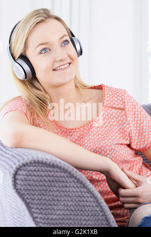 Junge Frau, die über drahtlose Kopfhörer Musik hören Stockfoto