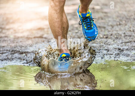 Mann geht in eine Pfütze planschen seine Schuhe läuft. Cross Country Trail. Frieren Aktion ein Stockfoto