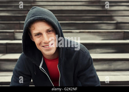 Porträt des jungen urbanen Sportler. Schwarzer Hoodie. Sitzt auf der Treppe Stockfoto