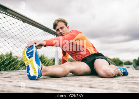 Sportler, die Strecken außerhalb auf Holzbrücke Stockfoto