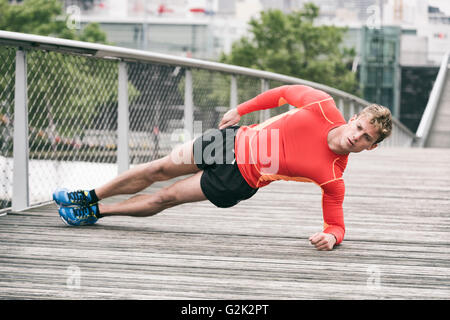 Sportler, die Beplankung Ausübung außerhalb auf Holzbrücke Stockfoto