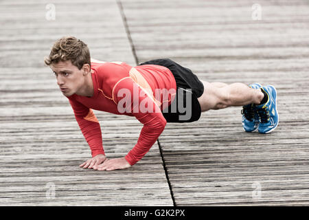 Junger sportlicher Mann tun Push Ups. Bewegung in der Natur. Stockfoto
