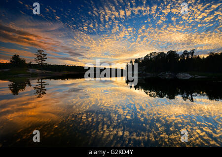 Wolken spiegeln sich in den nahen See bei Sonnenuntergang Kenora Ontario Canada Stockfoto