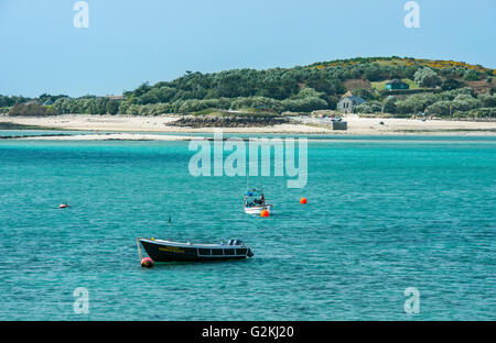 Tresco Kanal, das Wasser zwischen Tresco und Bryher, mit Bryher Kirche im Hintergrund und zwei Boote vertäut, Scillies Stockfoto