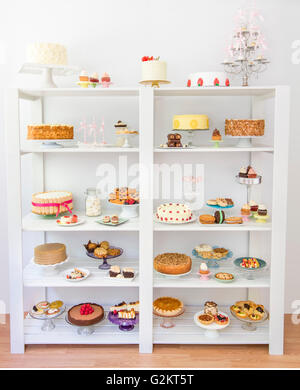 Verschiedene Desserts in weißen Regalen Stockfoto