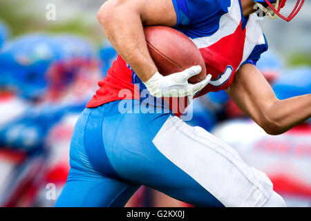 Seitenansicht des american-Football-Spieler, der läuft mit dem Ball, einen Touchdown zu machen. Stockfoto