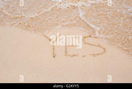 Ja - geschrieben im Sand am Strand Textur Stockfoto