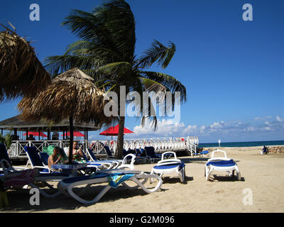 Schöne Sonne beleuchtet warmen karibischen Strand, goldenen Sand und dramatische Himmel, Decameron Hotel, Runaway Bay, mit Kokospalmen Stockfoto