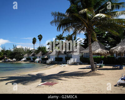 Schöne Sonne beleuchtet warmen karibischen Strand, goldenen Sand und dramatische Himmel, Decameron Hotel, Runaway Bay, mit Kokospalmen Stockfoto