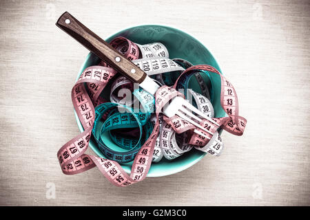 Diät essen gesunde Lebensweise und schlanken Körper Konzept. Viele Maßbändern in Schüssel auf Tisch mit Gabel, Ansicht von oben Stockfoto