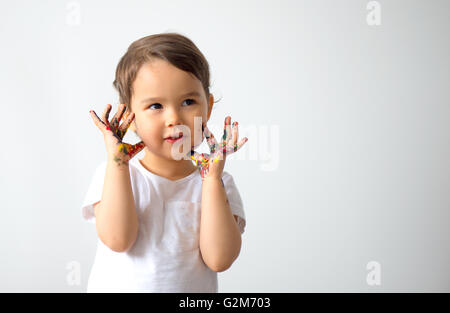 Lustige kleine Mädchen mit Händen in bunten Farben lackiert Stockfoto