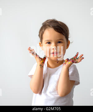 Lustige kleine Mädchen mit Händen in bunten Farben lackiert Stockfoto