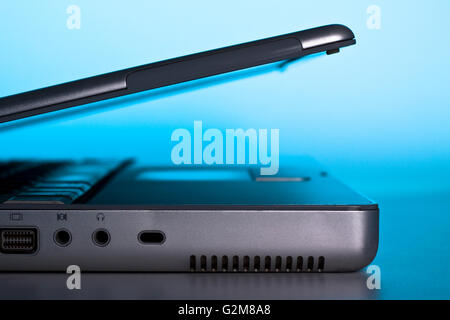 silberne Seite Ansicht Laptopdeckel offen mit blauer Hintergrundbeleuchtung Stockfoto