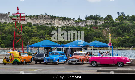 Vier farbige schön klassische Autos aus den 1950er Jahren warten auf der Seite der Malecon Ozean Autobahn in Havanna. Stockfoto